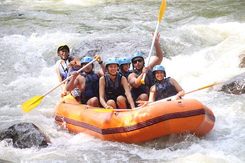 The group paddling a raft through white water on a river excursion