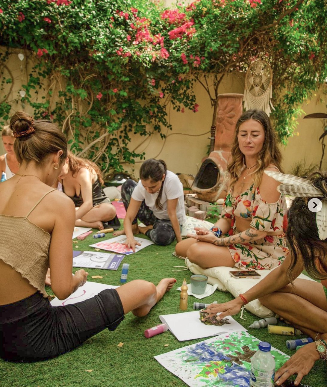 The group painting together in a garden art session beneath bougainvillea