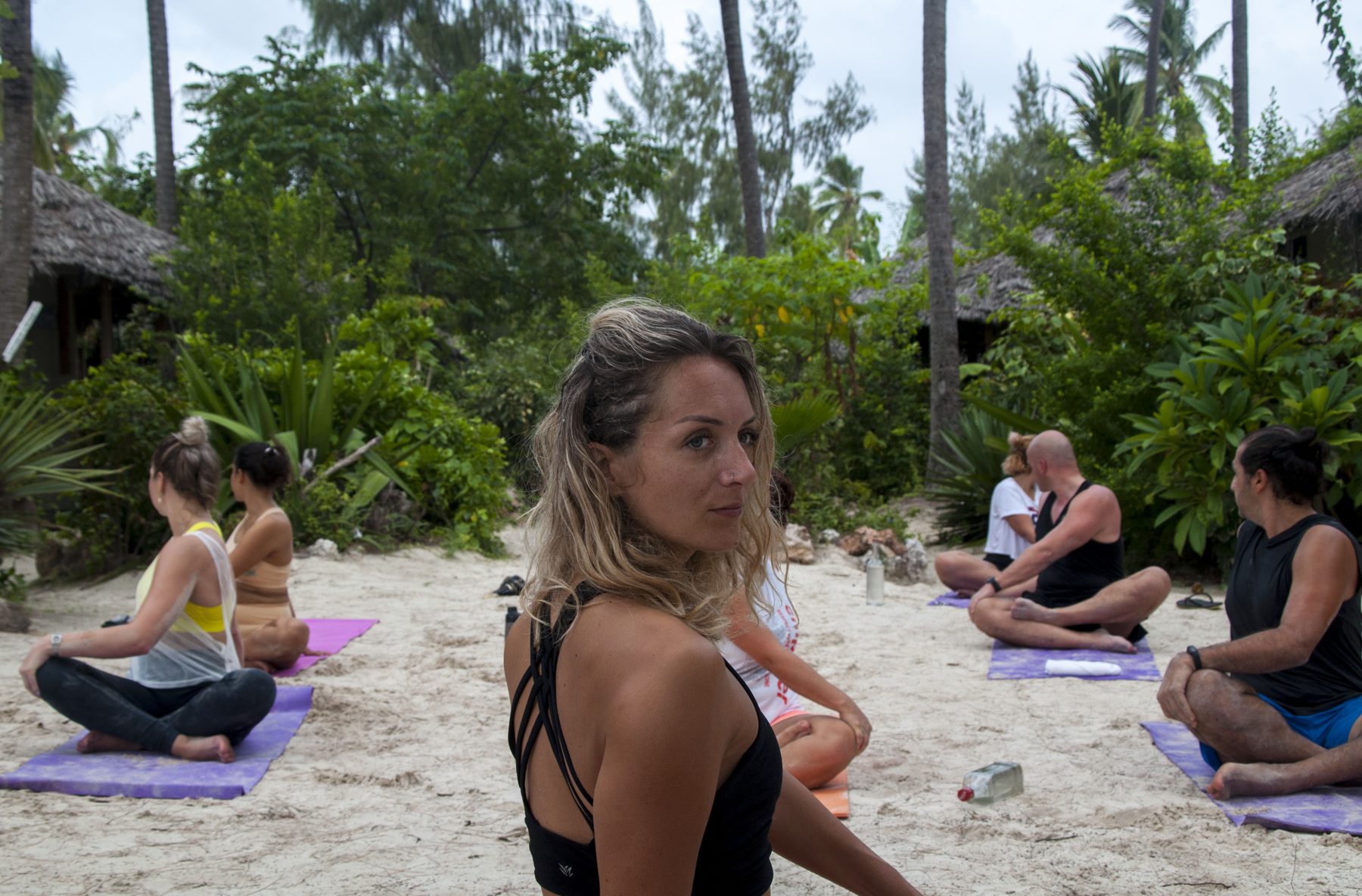 Guests seated in a morning movement circle on the beach